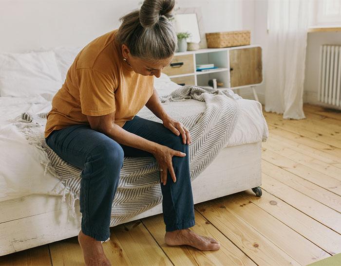 Lady sitting on bed holding knee